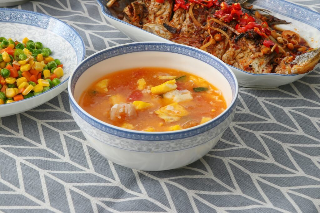 Top view of traditional Chinese fish and  Moroccan Fish Soup (Shorba Samak)tomato soup served with colorful vegetables.