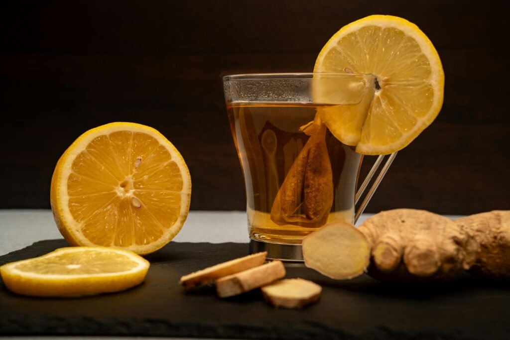 Moroccan Lemon & Ginger Infusion A warm cup of lemon ginger tea surrounded by fresh lemon slices and ginger root on slate.