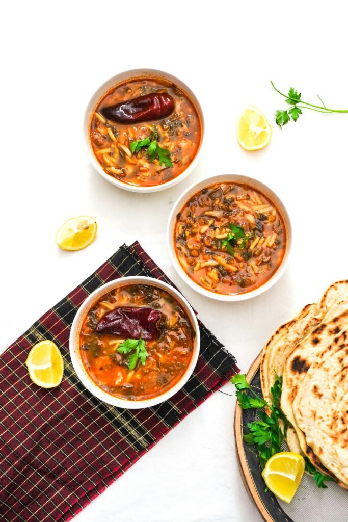 Tasty Moroccan Harira soup bowls with herbs, lemon slices, and fresh flatbread for a flavorful meal.
